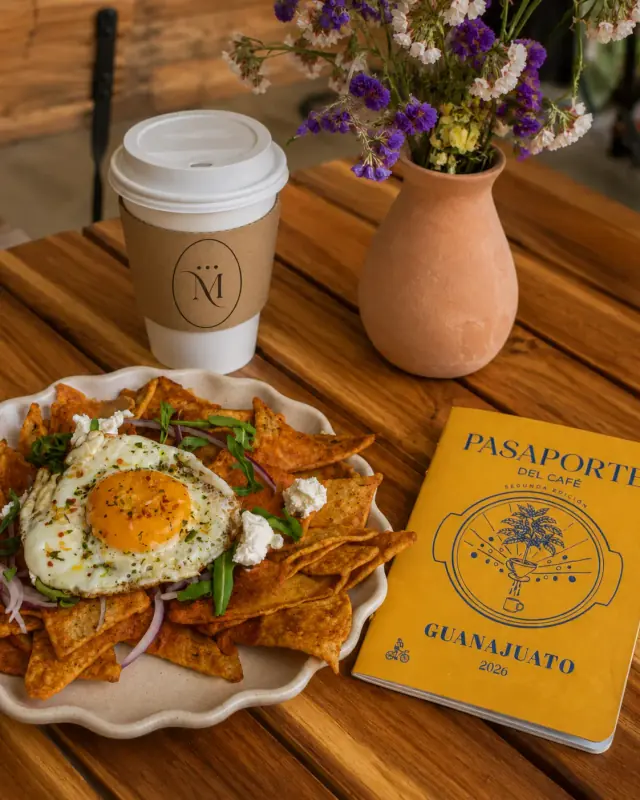 Pasaporte del Café de Makiepë junto a una charola de chilaquiles y café para llevar